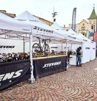 Il gazebo promozionale di Stevens Bikes è un gazebo pieghevole di 4x4 m di colore bianco. Le pareti laterali sono bianche e nere. Le biciclette sono posizionate sotto i gazebo pieghevoli.