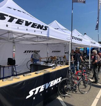 Gazebo per eventi 3x3m bianco personalizzato con logo Stevens bikes a evento sportivo di bicicletta con pareti laterali e pareti laterali a mezza altezza nere con banconi