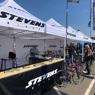 Gazebo per eventi 3x3m bianco personalizzato con logo Stevens bikes a evento sportivo di bicicletta con pareti laterali e pareti laterali a mezza altezza nere con banconi