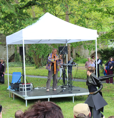 White 3x3 gazebo at a concert in a park covers a musician and his instruments 