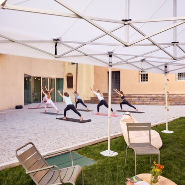 Gazebo Ecotent bianco 6x4m su gairdino davanti alla biblioteca di Bressanone utilizzato outdoor per corso di yoga rpara l'area relax dal sole