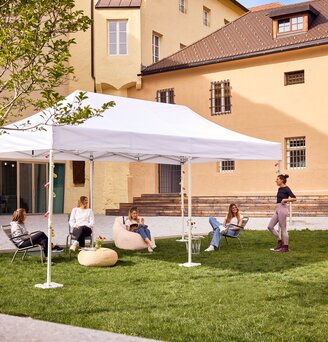 Der 6x3 m große Faltpavillon dient als Outdoor-Überdachung einer Bibliothek. Darunter sitzen Jugendliche.