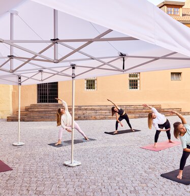 Gazebo Ecotent bianco 6x4m su gairdino davanti alla biblioteca di Bressanone utilizzato outdoor ripara l'insegnante del corso di ginnastica 