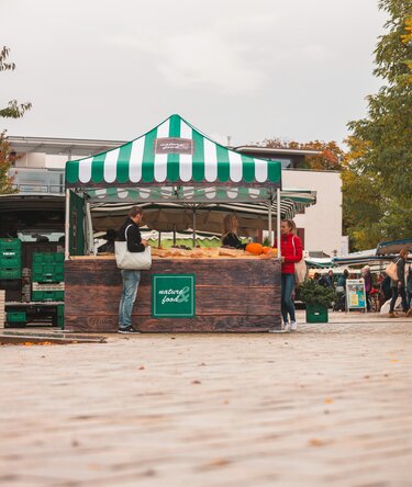 Gazebo pieghevole 3x3 m al mercato settimanale. Il gazebo pieghevole è completamente stampato, ha diverse pareti laterali e un bancone. Serve come stand di vendita per frutta e verdura.