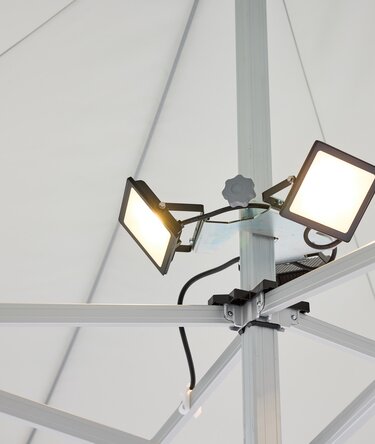 I fari LED, composto da 3 spot, è montato sul palo centrale del gazebo pieghevole. I fari LED sono accesi.