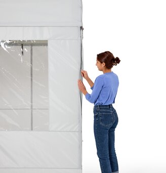 The woman is attaching the side walls to the folding gazebo. She closes them with a zip for complete all-round protection.