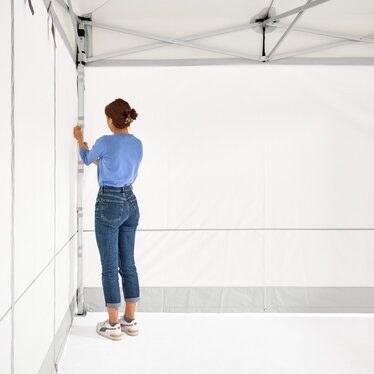 The woman assembles the 2 closed side walls on the folding gazebo.