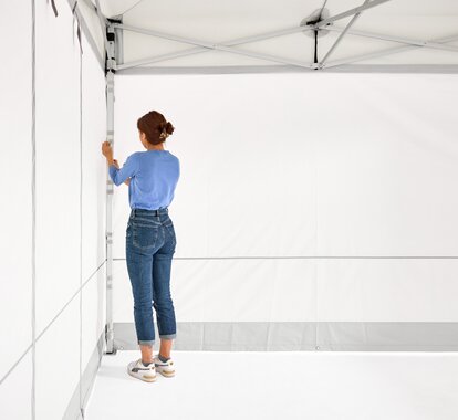 Die Frau montiert die  2 geschlossenen Seitenwände am Faltpavillon.
