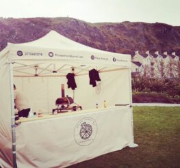 Weißer Faltpavillon mit Pizza-Stand und Ofen von Pizza Party NI bei einer Outdoor-Veranstaltung.