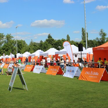 Weißer und orangefarbener 6x3-Faltpavillon mit dekorativen Eckvorhänge und personalisierten ING-DiBa-Fahnen bei einer gesponserten Sportveranstaltung in Deutschland